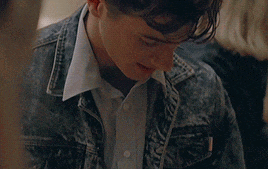 a close up of a man wearing a denim jacket and a white shirt .