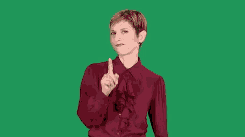 a woman in a red shirt is making a rude gesture with her middle finger .