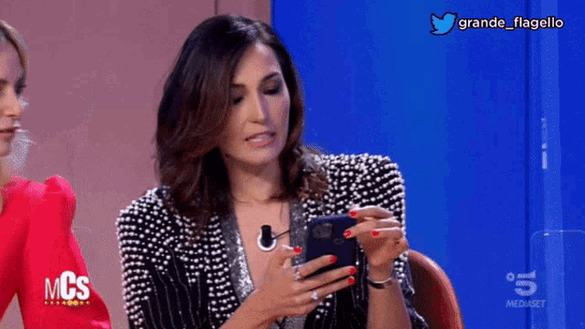 a woman holding a cell phone in front of a blue background that says mcs on it