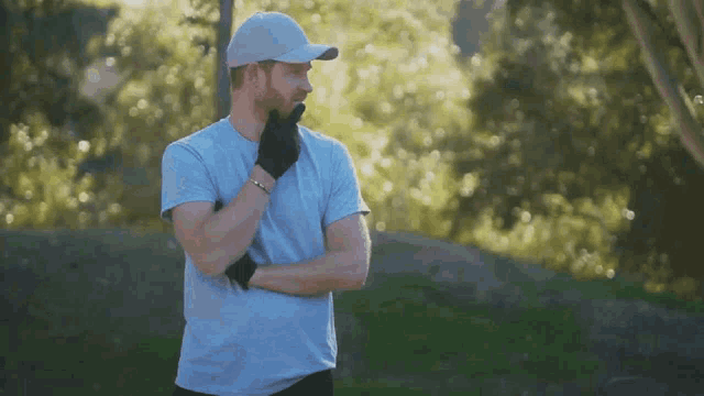 a man wearing a hat and gloves is standing in a park