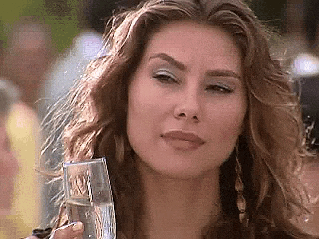 a woman with long hair is holding a glass of water in her hand