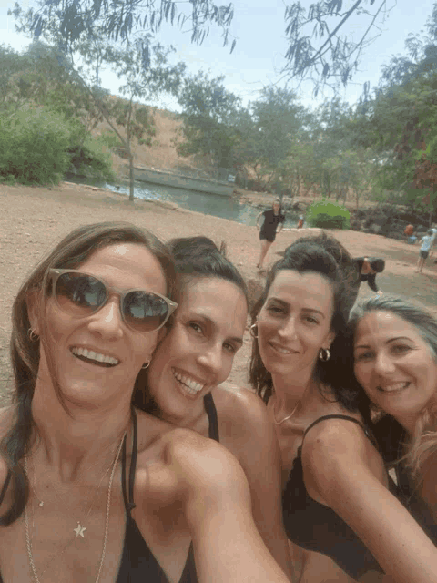 four women are posing for a picture and one of them has a star necklace