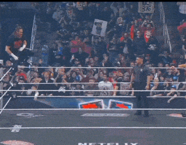 a man is taking off his shirt in a wrestling ring with the word raw behind him