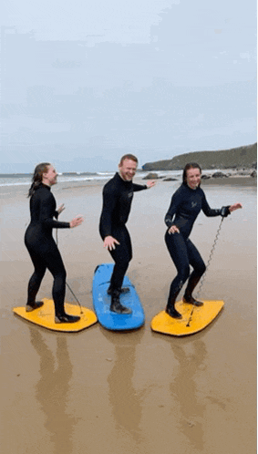three people are riding surfboards on a beach .