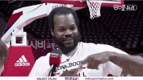 a man with a beard is sitting in front of a microphone while playing basketball .