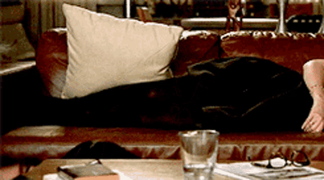 a woman laying on a couch with a glass of water on the table