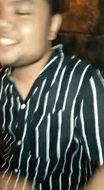 a man is wearing a black and white striped shirt and smiling .