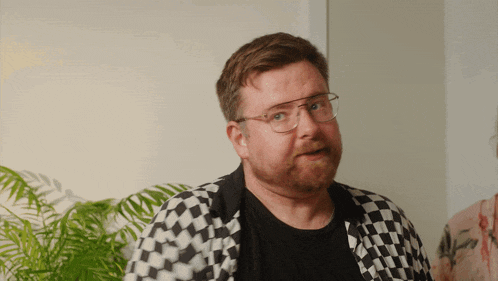 a man with glasses and a beard wearing a black and white checkered jacket