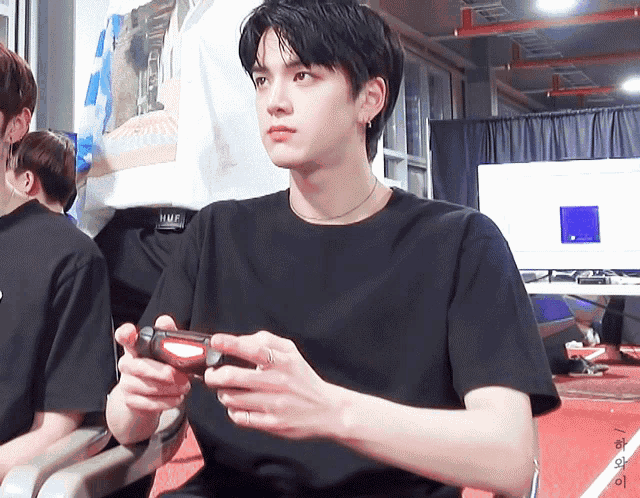 a man in a black t-shirt is holding a video game controller