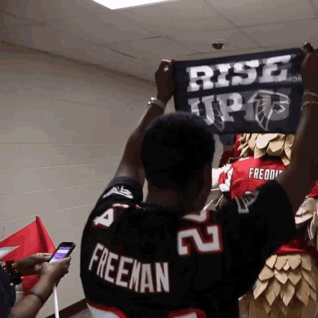 a man in a freeman jersey is holding up a sign