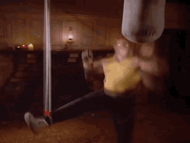a man in a yellow tank top and red headband is hanging from a rope