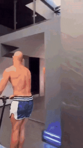 a man without a shirt is riding a bike in a gym
