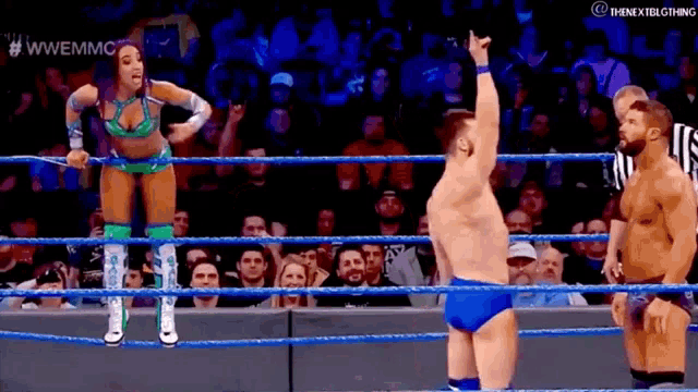 a woman is standing in a wrestling ring with a referee and a man standing behind her .