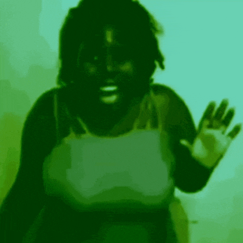 a woman in a green tank top is waving