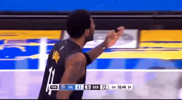 a basketball player wearing a number 11 jersey stands in front of a scoreboard