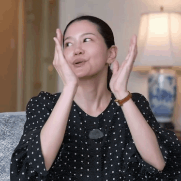 a woman wearing a black polka dot shirt is making a face