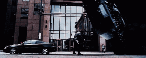 a black car is driving down a street in front of a large building