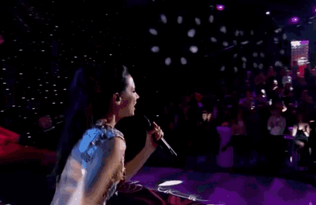 a woman singing into a microphone on stage