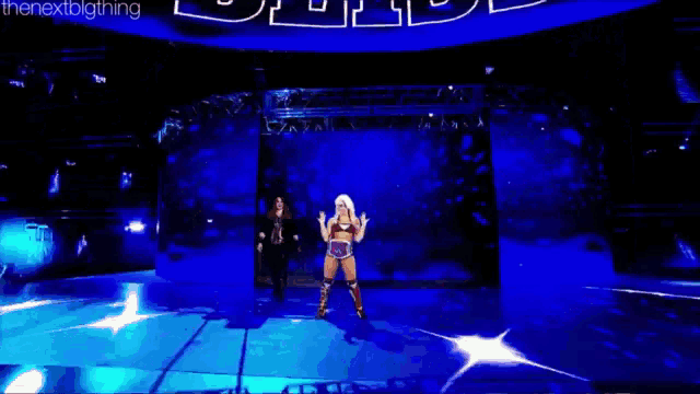 two women are standing on a stage in front of a blue screen with the words the next big thing on it .
