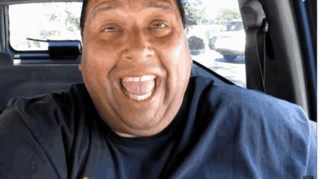 a man with his tongue hanging out is wearing a blue shirt