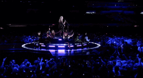 a group of people are dancing on a stage in front of a crowd that is watching