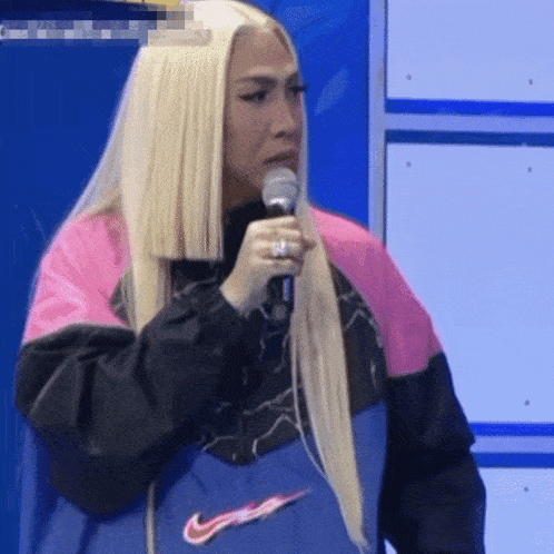 a woman with long blonde hair is holding a microphone
