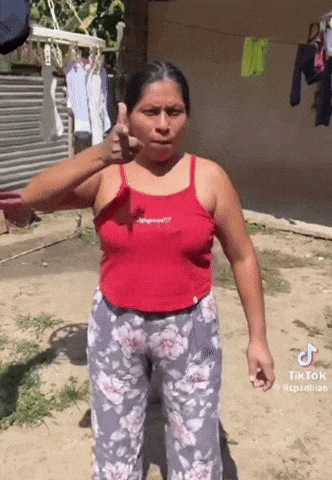 a woman in a red tank top is giving a thumbs up sign