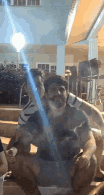 a man is holding a light saber while another man sits behind him
