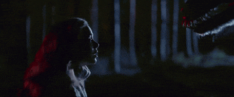a woman with red hair is looking at a monster in the woods