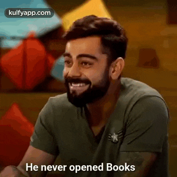 a man with a beard is smiling and saying `` he never opened books '' while sitting at a table .