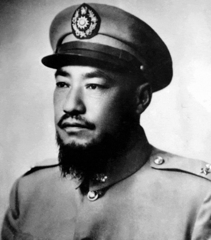 a man with a beard is wearing a hat with a medallion on it
