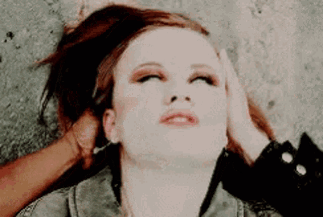 a woman is laying on the ground with her head in someone 's hand .