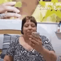 a woman is looking at her cell phone in front of a wall .