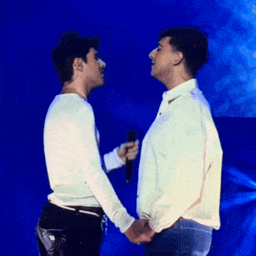 two men standing next to each other holding hands