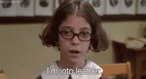 a young girl wearing glasses is sitting in a chair and says `` i 'm into leather '' .