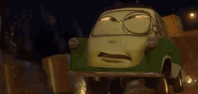 a green car from the movie cars is driving down a street at night .