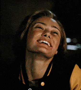 a young woman wearing a yellow and black jacket smiles