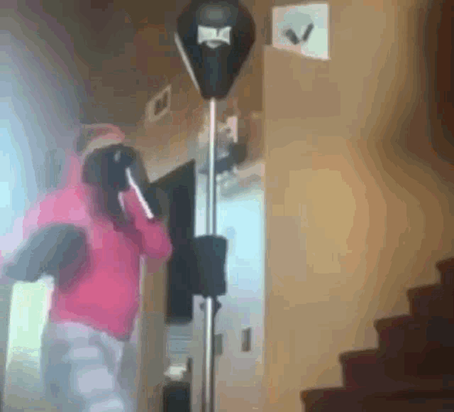 a person wearing boxing gloves is hitting a punching bag in a hallway .