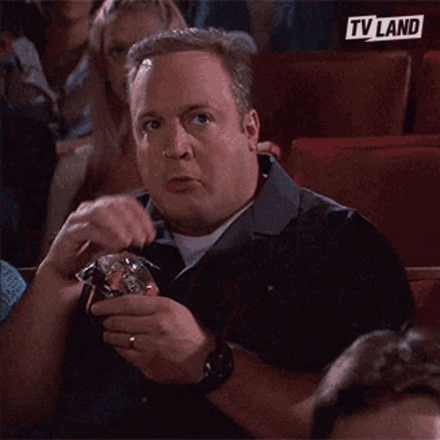 a man is sitting in a theater with a tv land logo on the back of his shirt