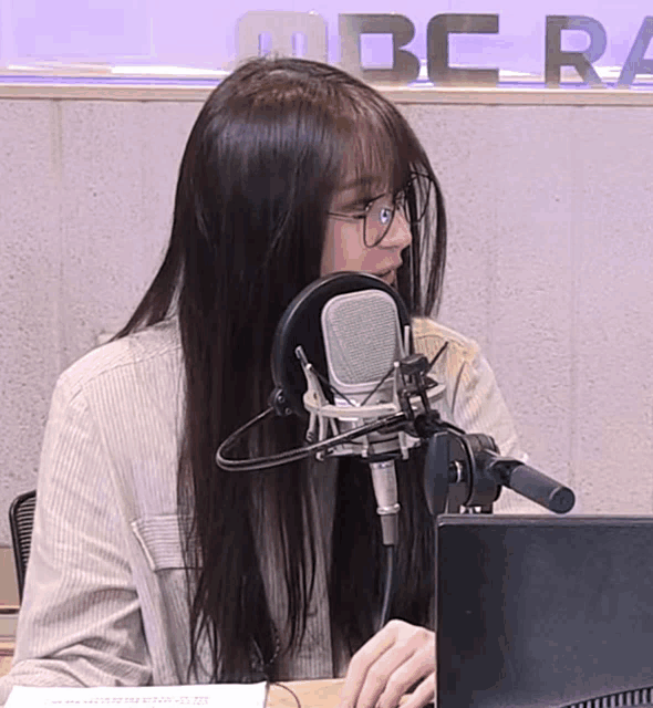 a woman with long hair is sitting in front of a microphone in front of a sign that says bbc radio