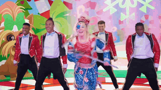 a group of men and a woman are dancing in front of a colorful background