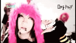 a woman wearing a pink wig and a cat ear hat is standing in front of a group of people .