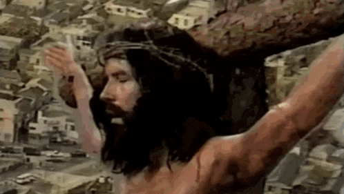 a man with a crown of thorns is hanging on a cross with his arms outstretched .