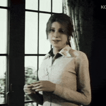 a woman in a white shirt stands in front of a window with kc written on the bottom right