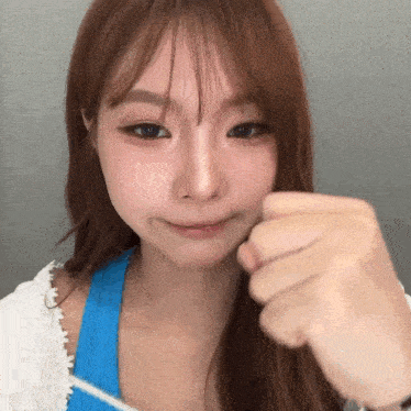 a close up of a woman 's face with her fist in the air