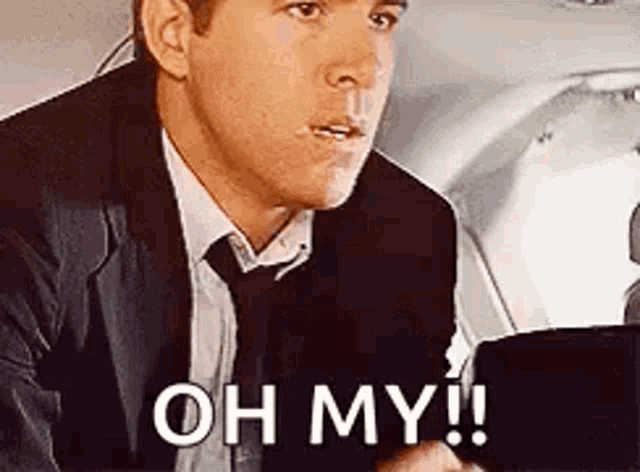 a man in a suit and tie is sitting in the back seat of an airplane and saying `` oh my ! ''