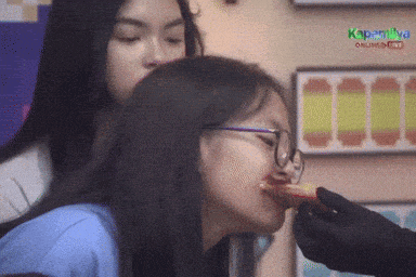a woman with glasses is being fed a piece of food by another woman ..