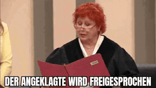 a woman with red hair is sitting in a courtroom holding a red folder .