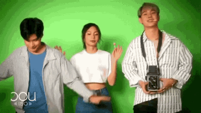 three people are standing next to each other on a green screen .