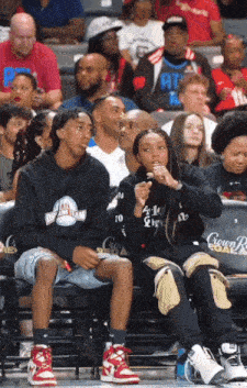 a group of people sitting in a stadium with one wearing a hoodie that says ' atlanta dream team '